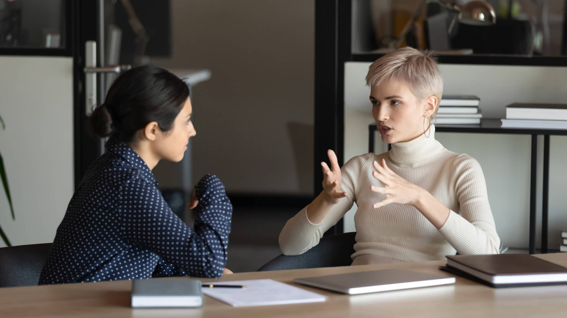 Frequently Asked Questions Two young woman speaking together at a table